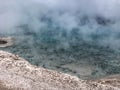 Aqua colored geyser with steam coming out of it