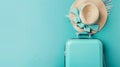 Aqua green travel suitcase and straw hat on a aqua green background