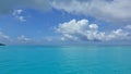 The aquamarine ocean is calm. There are picturesque cumulus clouds in the azure sky.