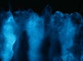 Aquarelle painted bright light blue neon watercolor on deep black paper background Royalty Free Stock Photo