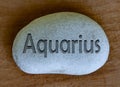 Aquarius zodiac sign text engraved on a stock with wooden background. Zodiac signs concept