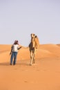 Arab Bedouin man with his camel in the Desert in Abu Dhabi western region Liwa Desert in United Arab Emirates