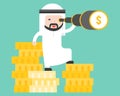 Arab business man stands on stack of gold coin using monocular