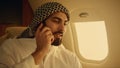 Arab businessman talking cell phone in airplane closeup. Confident man traveling Royalty Free Stock Photo