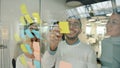 Arab businessman using glassboard with sticky notes sharing ideas with coworkers clapping hands