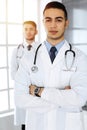 Arab doctor man standing with caucasian colleague in medical office or clinic. Diverse doctors team, medicine and
