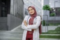 Arab female doctor or medical student, posing and smiling with folded arms, standing outside Royalty Free Stock Photo