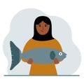 A arab female fisherman holds a large fish, proud of good fishing or hunting. Hobby, fishing concept. Royalty Free Stock Photo