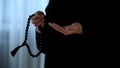 Arab female in hijab counting prayers by rosary in hand, religious forgiveness