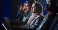 Arab Female Sitting in a Dark Crowded Auditorium at a Human Rights Conference. Young Muslim Woman Royalty Free Stock Photo