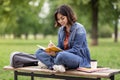 Arab female student writing in notebook while sitting on bench in park Royalty Free Stock Photo