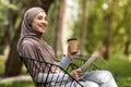 Arab girl with digital tablet drinking coffee at park