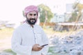 Arab Islam Muslim adult male from Saudi Arabia portrait happy smile standing outdoors with smart phone Royalty Free Stock Photo