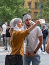 Arab-looking Boy and Girl who are Using a Smartphone to take a Picture of Themselves in Public Square