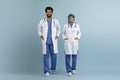 Arab male and female doctors in white uniform posing over blue background Royalty Free Stock Photo