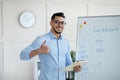 Arab male teacher showing thumb up near blackboard, teaching English on web, recommending online foreign language school