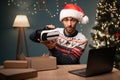 Arab male vlogger in Santa hat unboxing parcel with VR Glasses at camera, webcam view. POV muslim man recording video