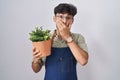 Arab man with beard holding green plant pot shocked covering mouth with hands for mistake Royalty Free Stock Photo