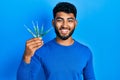 Arab man with beard holding picklock to unlock security door looking positive and happy standing and smiling with a confident