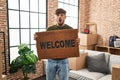 Arab man with beard holding welcome doormat afraid and shocked with surprise and amazed expression, fear and excited face Royalty Free Stock Photo