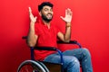 Arab man with beard sitting on wheelchair celebrating crazy and amazed for success with arms raised and open eyes screaming