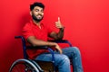 Arab man with beard sitting on wheelchair doing happy thumbs up gesture with hand