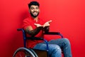 Arab man with beard sitting on wheelchair smiling with hands palms together receiving or giving gesture Royalty Free Stock Photo