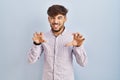 Arab man with beard standing over blue background smiling funny doing claw gesture as cat, aggressive and sexy expression Royalty Free Stock Photo