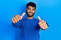 Arab man with beard wearing casual blue sweater approving doing positive gesture with hand, thumbs up smiling and happy for
