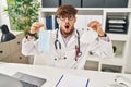 Arab man with beard wearing doctor uniform holding medical mask in shock face, looking skeptical and sarcastic, surprised with Royalty Free Stock Photo