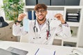 Arab man with beard wearing doctor uniform holding medical mask winking looking at the camera with sexy expression, cheerful and Royalty Free Stock Photo
