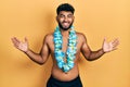 Arab man with beard wearing swimsuit and hawaiian lei celebrating victory with happy smile and winner expression with raised hands Royalty Free Stock Photo