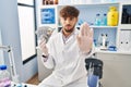 Arab man with beard working at scientist laboratory holding money with open hand doing stop sign with serious and confident