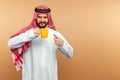 Arab man businessman in national dress holds a cup in his hands. Dishdasha, kandora, thobe, middle east traditional menswear