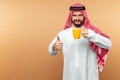 Arab man businessman in national dress holds a cup in his hands. Dishdasha, kandora, thobe, middle east traditional menswear