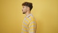 Arab man in his relaxed yet serious stance, looking off to the side against an isolated yellow cutout background