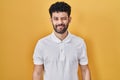 Arab man standing over yellow background winking looking at the camera with sexy expression, cheerful and happy face