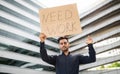 arab man stands against urban backdrop holding NEED WORK sign Royalty Free Stock Photo