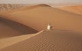 Arab man in traditional outfit sitting in the Arabian desert and enjoying the landscape