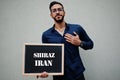 Arab man wear blue shirt and eyeglasses hold board with Shiraz Iran inscription. Largest cities in islamic world concept Royalty Free Stock Photo