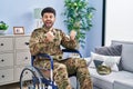 Arab man wearing camouflage army uniform sitting on wheelchair celebrating surprised and amazed for success with arms raised and