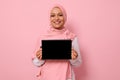 Arab Muslim beautiful woman wearing pink hijab, smiling toothy smile looking at camera, standing against pink background with copy