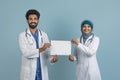 Arab muslim male and female doctors in white coats holding blank placard Royalty Free Stock Photo