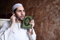 Arab muslim man with Koran islamic holy book and headset Royalty Free Stock Photo