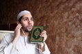 Arab muslim man with Koran islamic holy book and headset Royalty Free Stock Photo
