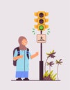 arab schoolgirl with backpack waiting for green traffic light to cross road on crosswalk road safety concept