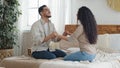 Arab spaniard man and woman, boyfriend and girlfriend, ethnic husband and wife, married couple sitting on bed in cozy