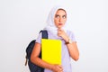 Arab student girl wearing hijab and backpack holding book over isolated white background serious face thinking about question, Royalty Free Stock Photo