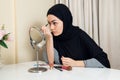 Arab woman applying makeup on her face, wearing traditional Arabian dress