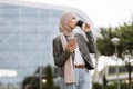 Arab woman in headscarf walking on the street with take away coffee and phone